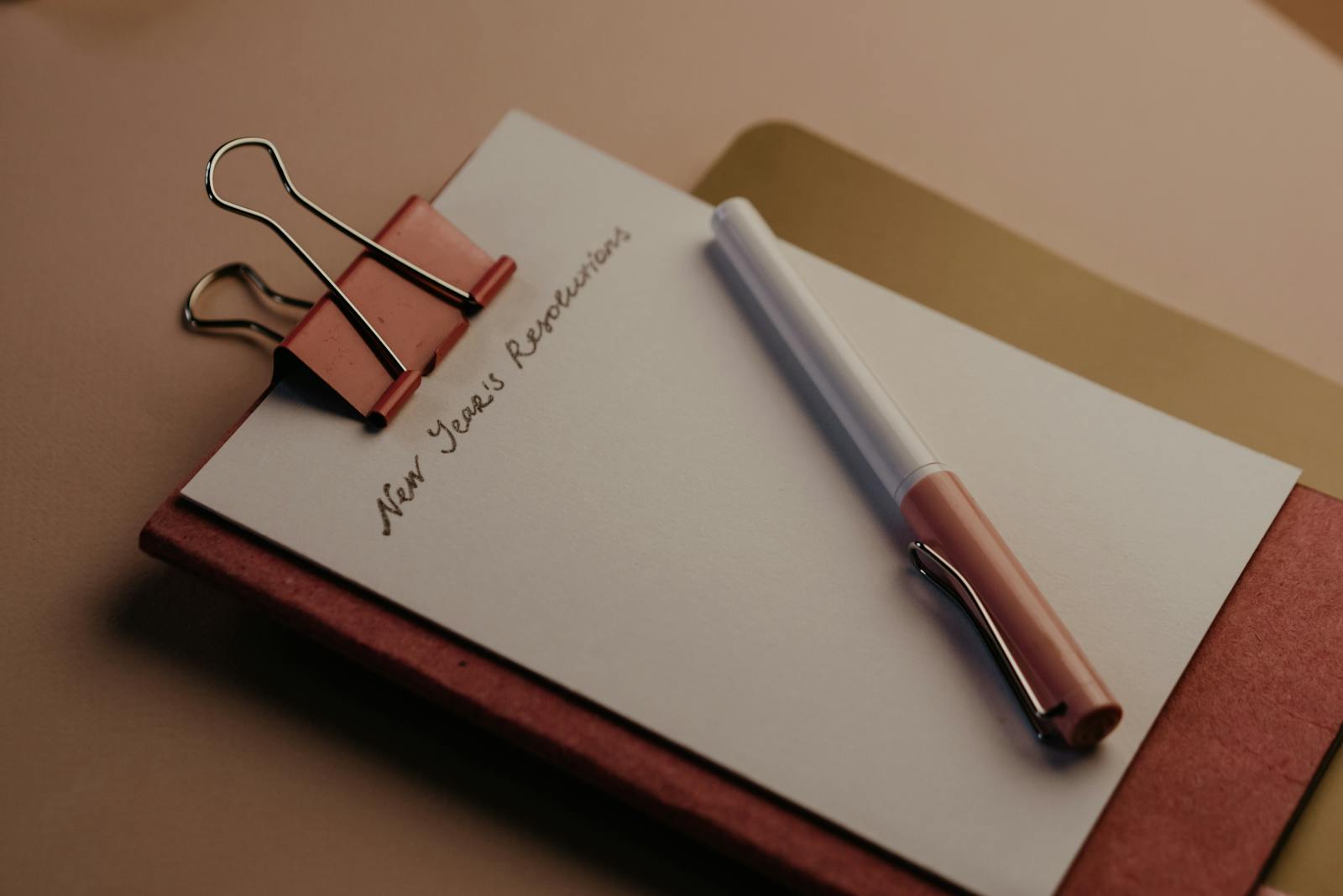 A stylish New Year's resolution planner with pen and paper clip on desk.